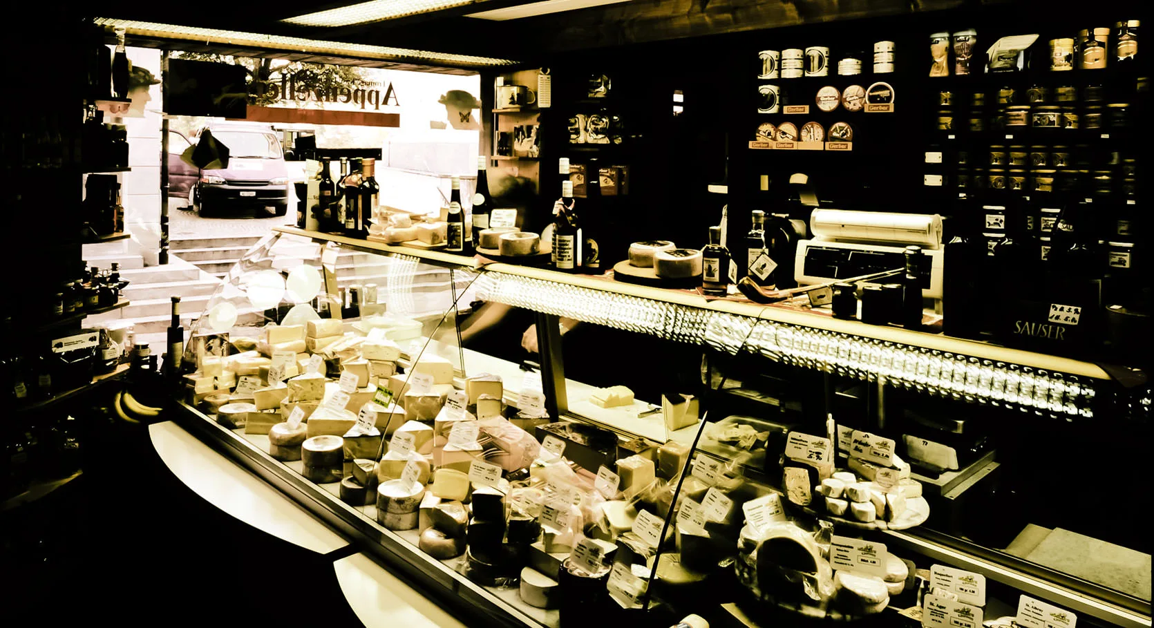 Inside an Appenzeller cheese shop, a case full of wheels of cheese and shelves of jars, Switzerland