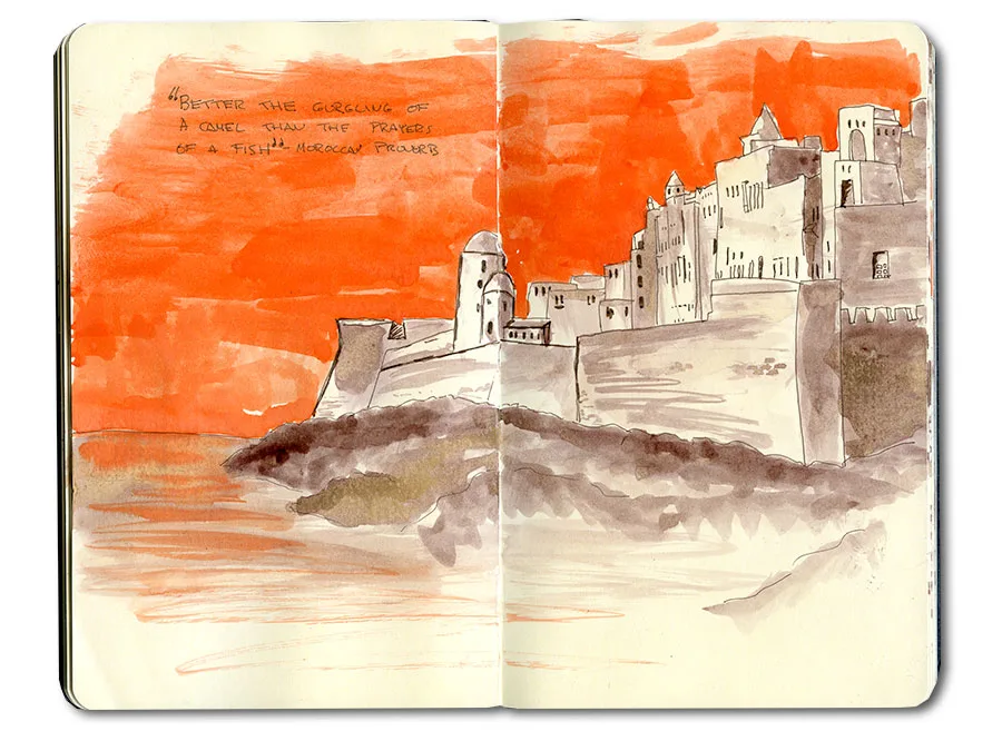 Ink and watercolor sketchbook spread of a walled Moroccan coastal fortress on rocks beneath a vivid orange sky.