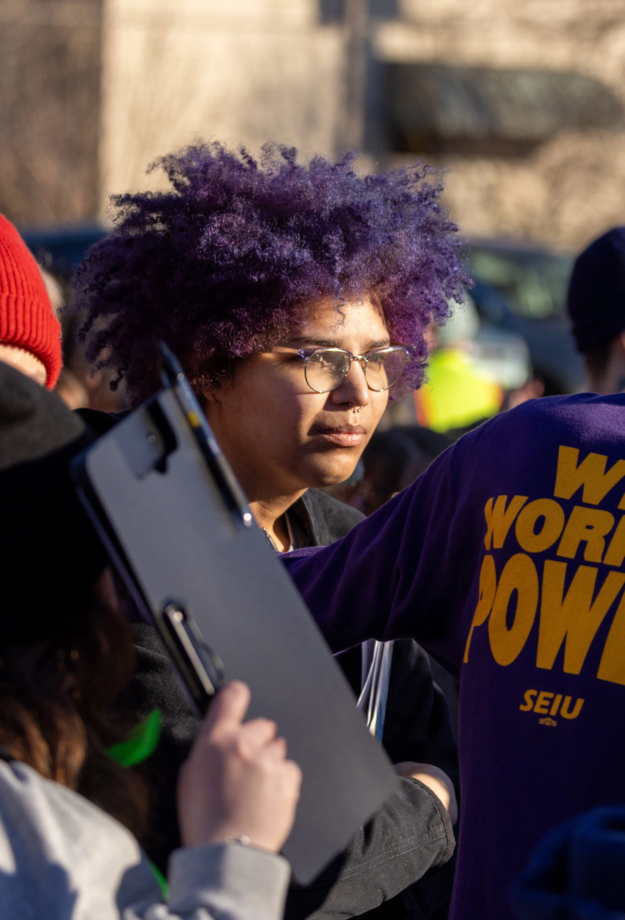 A close-up portrait of a participant at the Alex Pretti vigil and protest in Minneapolis on President's Day 2026, showing a thoughtful expression among the crowd gathered in support of immigrant justice.