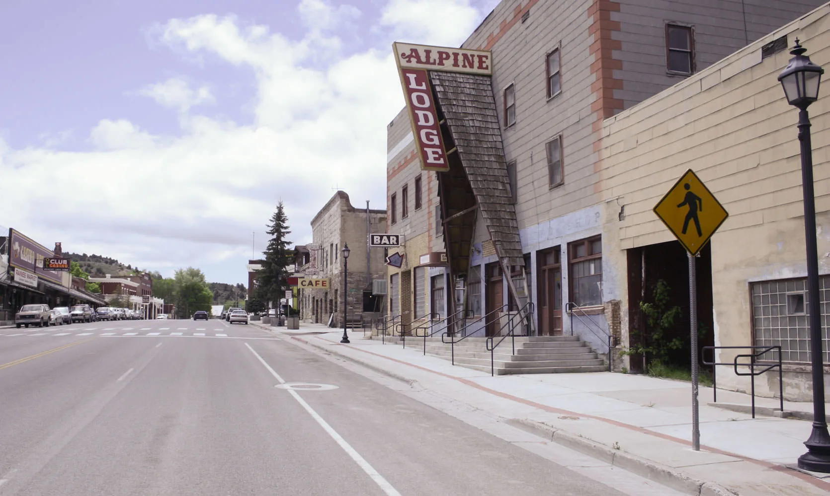 The Alpine Lodge's tall vintage sign over an empty main street in a small Nevada highway town, casino and cafe signs down the block