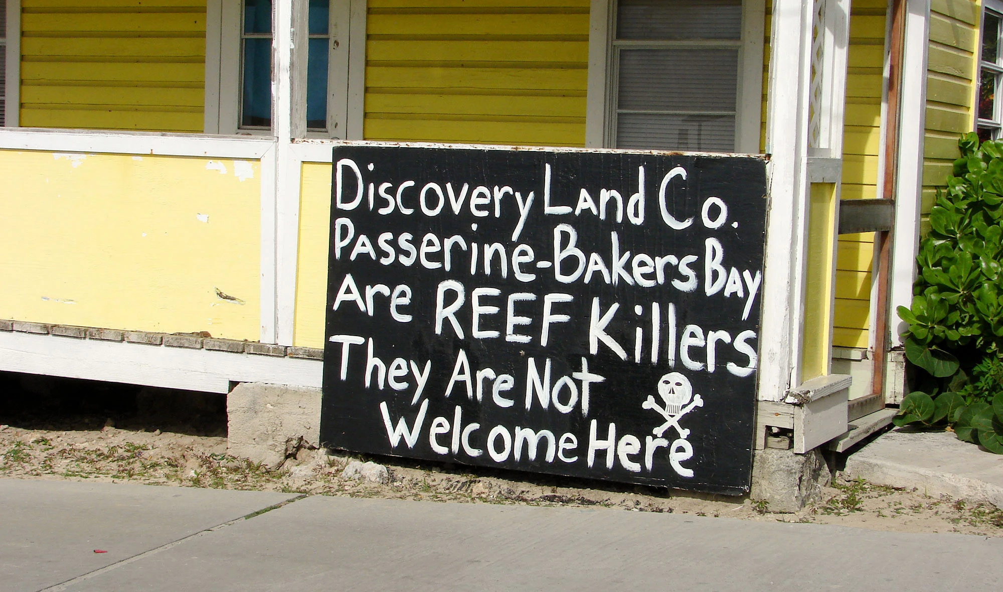 A hand-painted sign in the Great Guana Cay settlement reads: "Discovery Land Co. Passerine-Bakers-Bay are REEF Killers. They are Not Welcome Here."