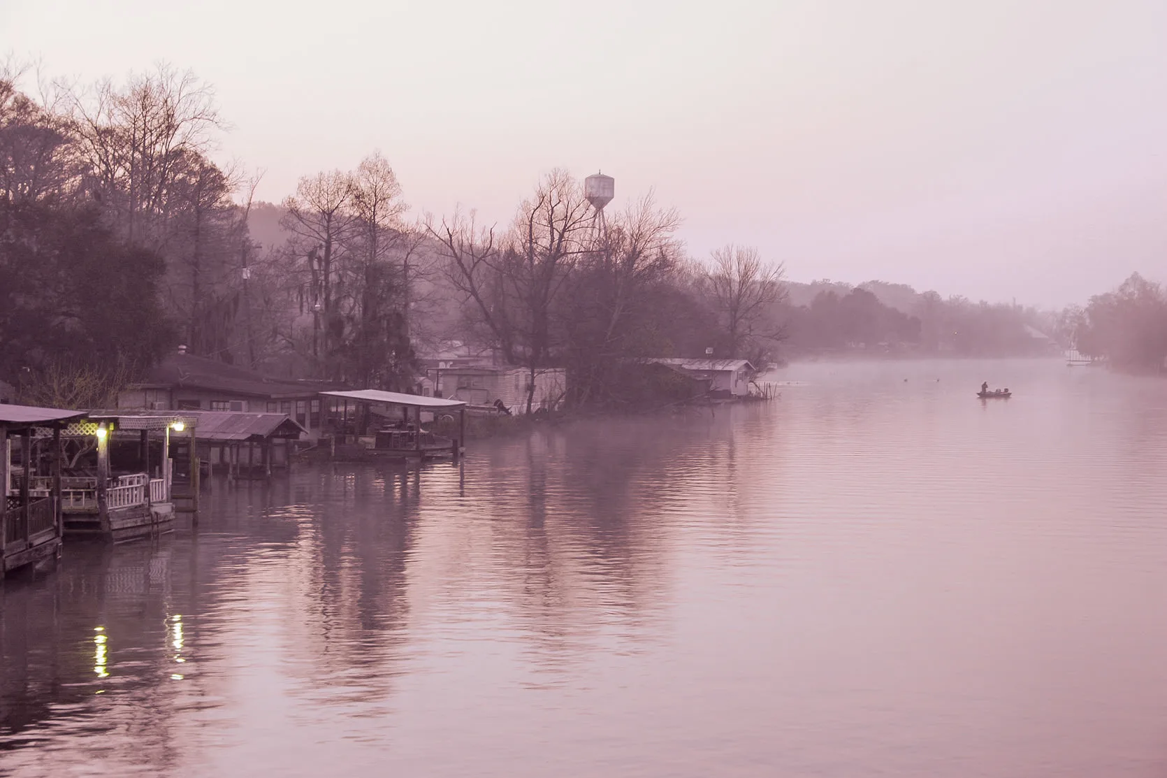 Stilt houses and boats along a misty bayou in Stephensville, Louisiana, at dawn.