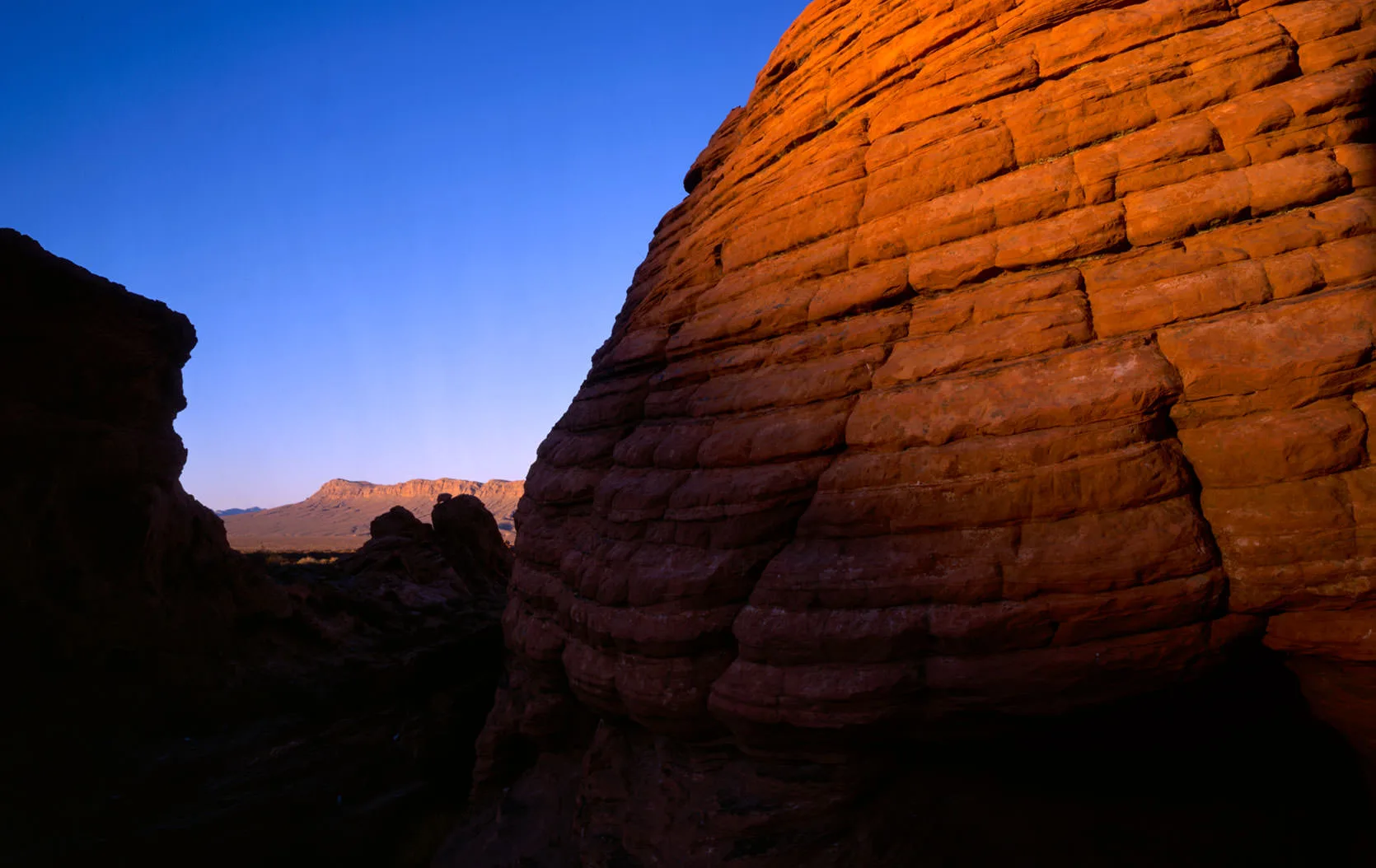 The striped, dome-shaped sandstone of the Beehives glowing orange at dusk in Valley of Fire State Park, Nevada.