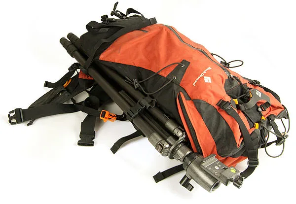 An orange-and-black Black Diamond backpack with a camera tripod strapped along its side