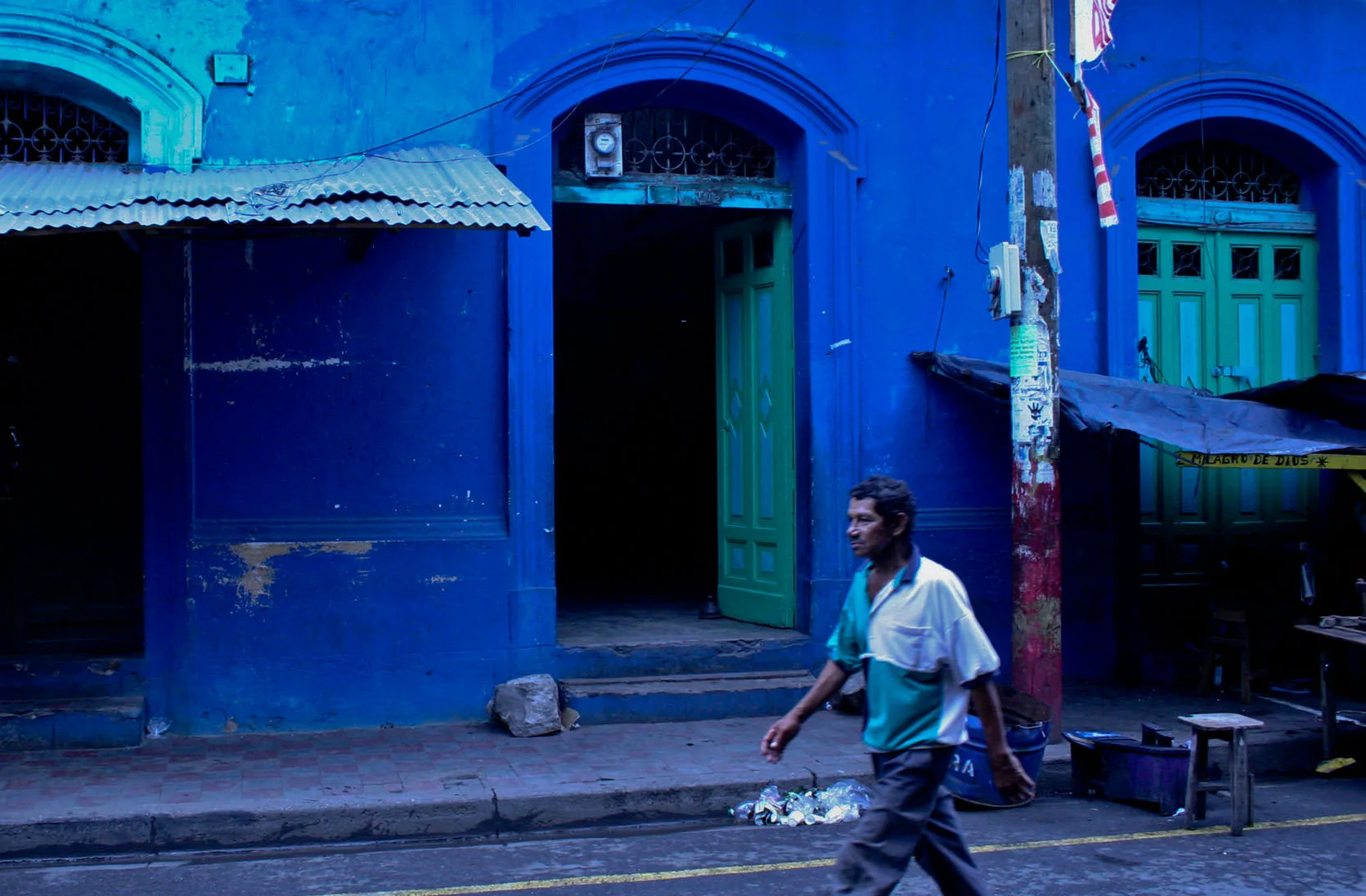 A man walking past the deep-blue colonial walls and green doors of a Granada street, Nicaragua