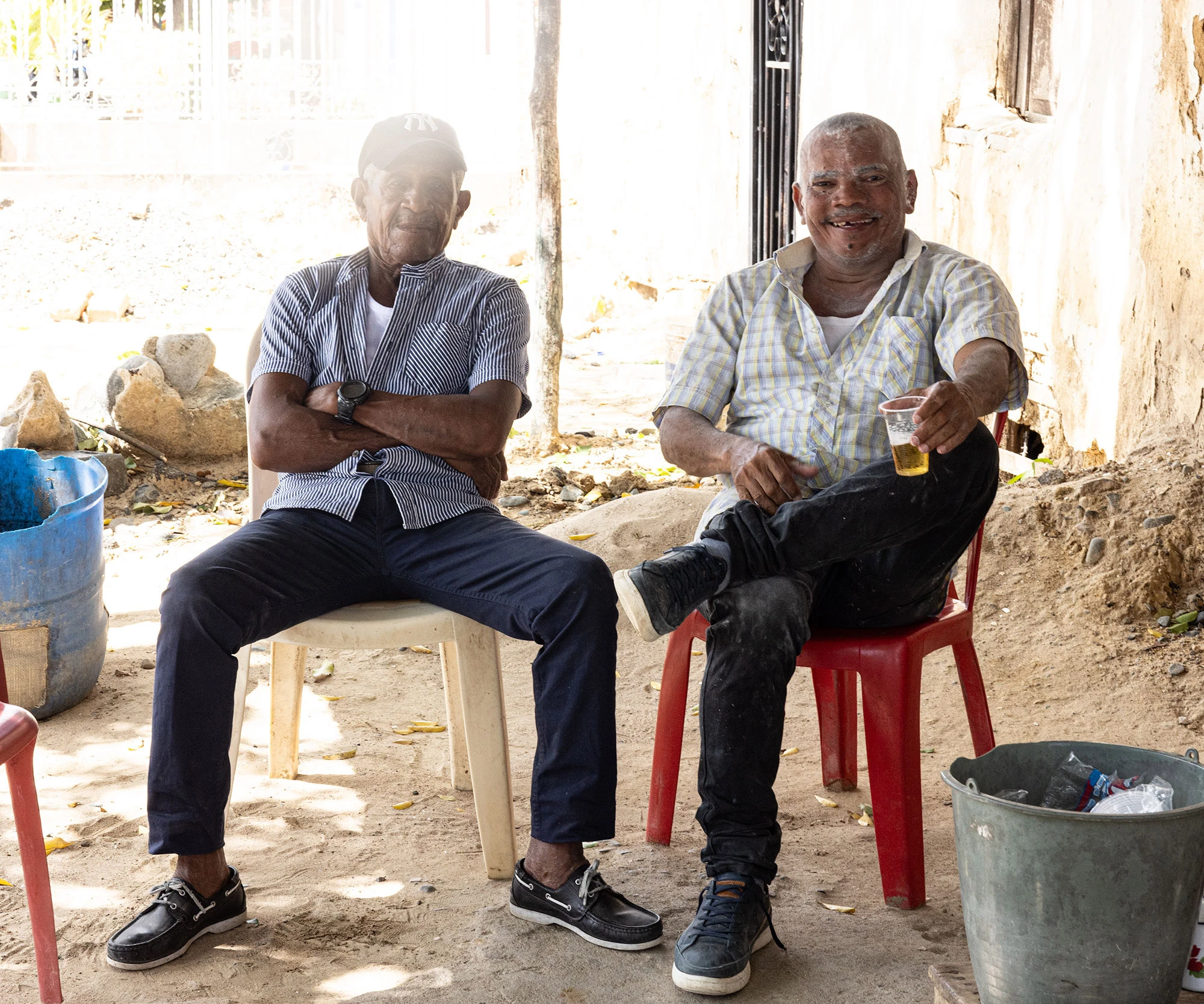 Two men in Camarones, Colombia, smile and laugh beneath the warm glow of candles during the Festival of Candles. Their joy is reflected in the flickering lights and soft shadows of the evening celebration, part of a beloved December tradition in the Guajira region.