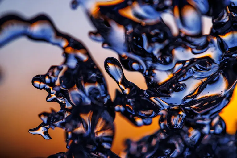 An abstract close-up of melting ice shapes glowing against an orange and blue sunset.
