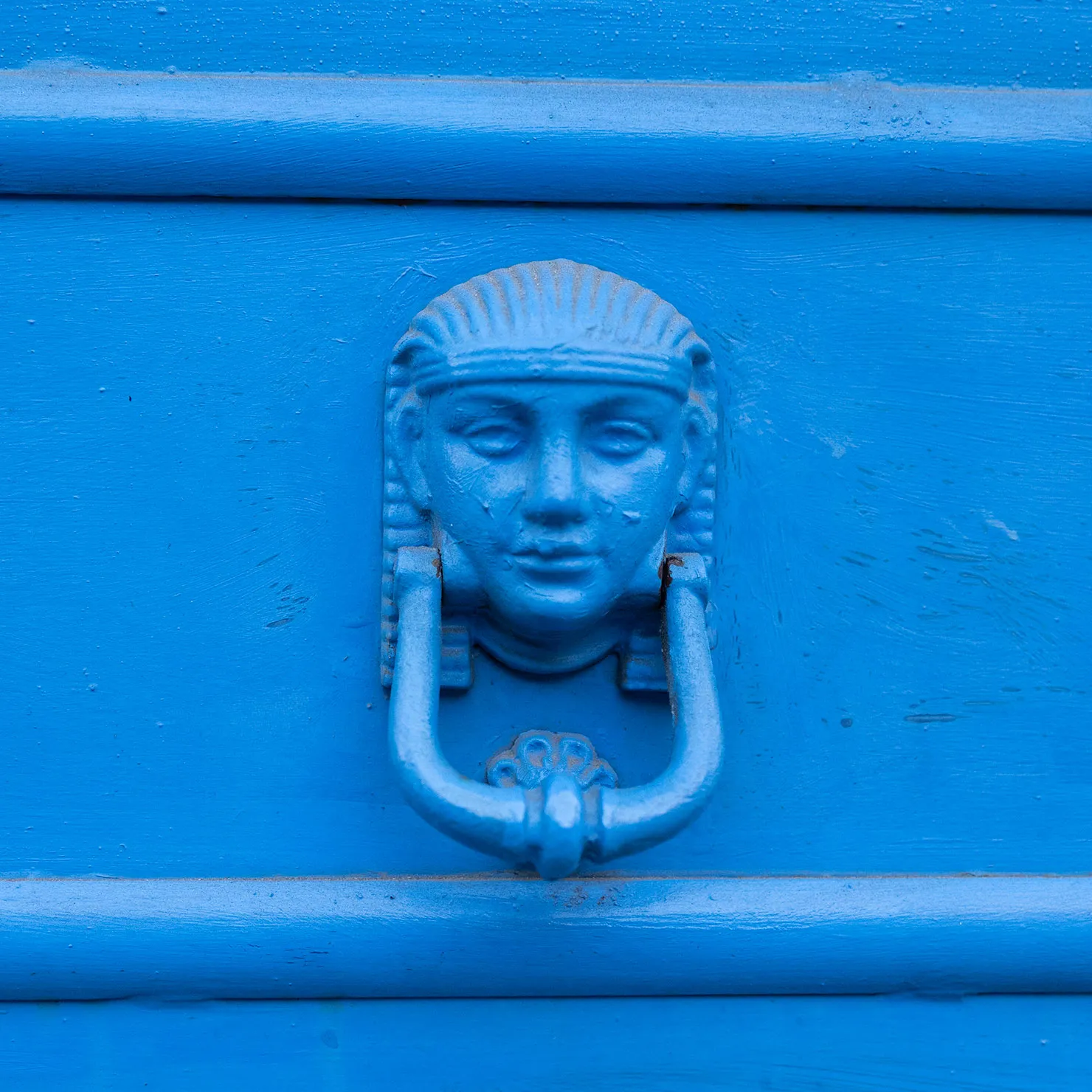 Pharaoh-head door knocker painted bright blue to match its door in Palermo, Sicily.