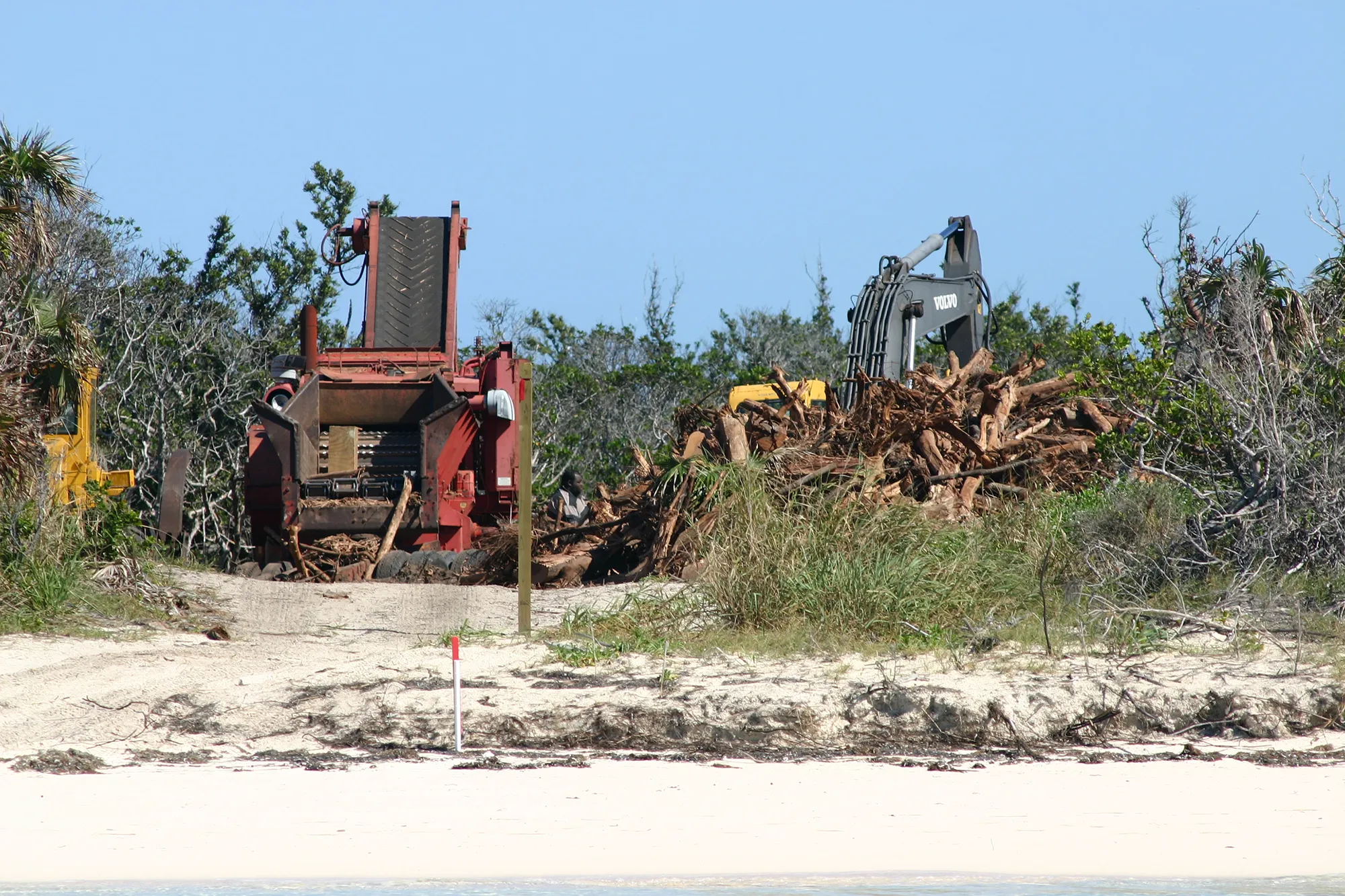 Heavy machinery and piles of uprooted trees behind the beach at Bakers Bay, Great Guana Cay