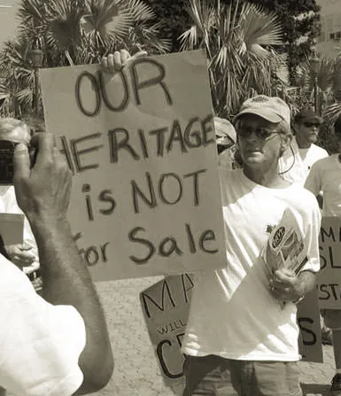 Protesters holding a hand-painted sign reading "Our heritage is not for sale" on Great Guana Cay, Bahamas.