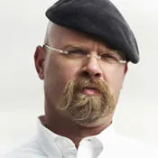 Portrait of Jamie Hyneman in a black beret, with a walrus mustache and glasses.