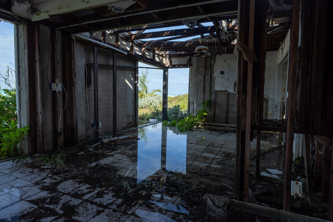 A storm-gutted house with a flooded tile floor, open to the sea