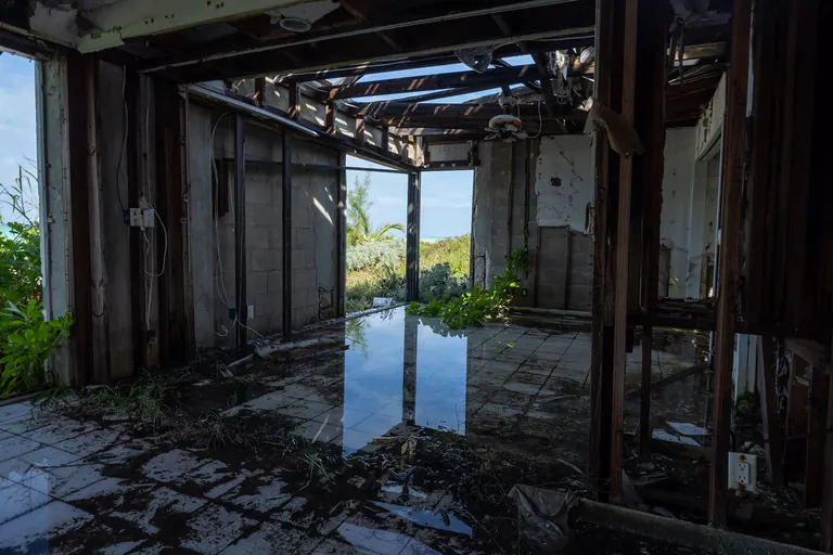 A storm-gutted house with a flooded tile floor, open to the sea