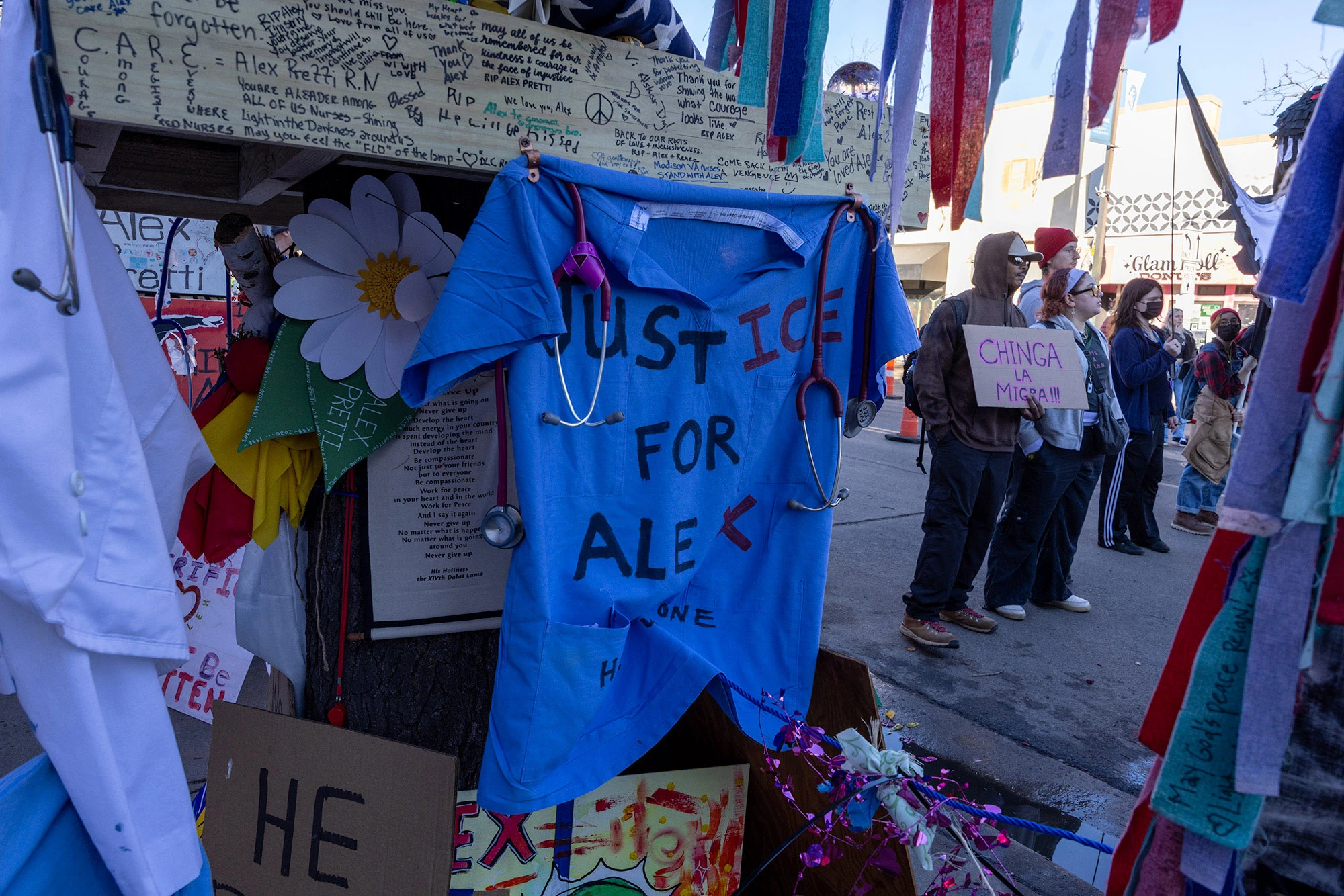 A pair of teal nurses' scrubs at the Alex Pretti memorial in Minneapolis, hand-painted with the words 'Justice for Alex.'
