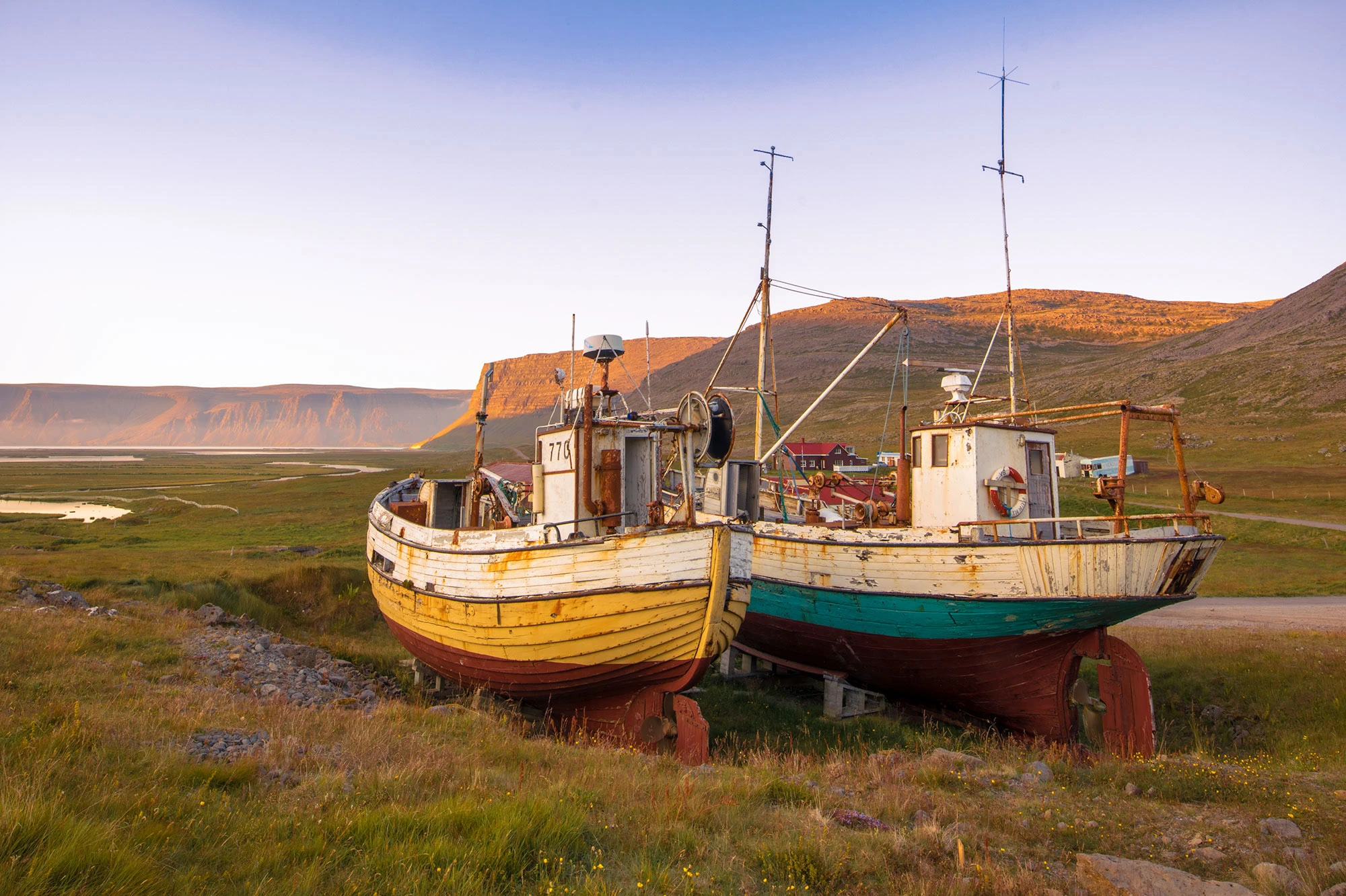 Traditional Southern Westfjords fishing vessels on display on the grounds of the Hnjotur Museum. Faded yellow and turquoise paint on the hulls.
