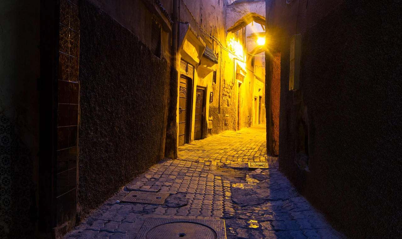 A narrow lantern-lit alley in the Marrakech medina at night.
