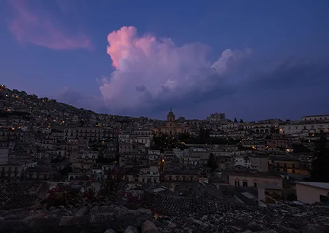 Modica at dusk, its old town stacked up the hillside
