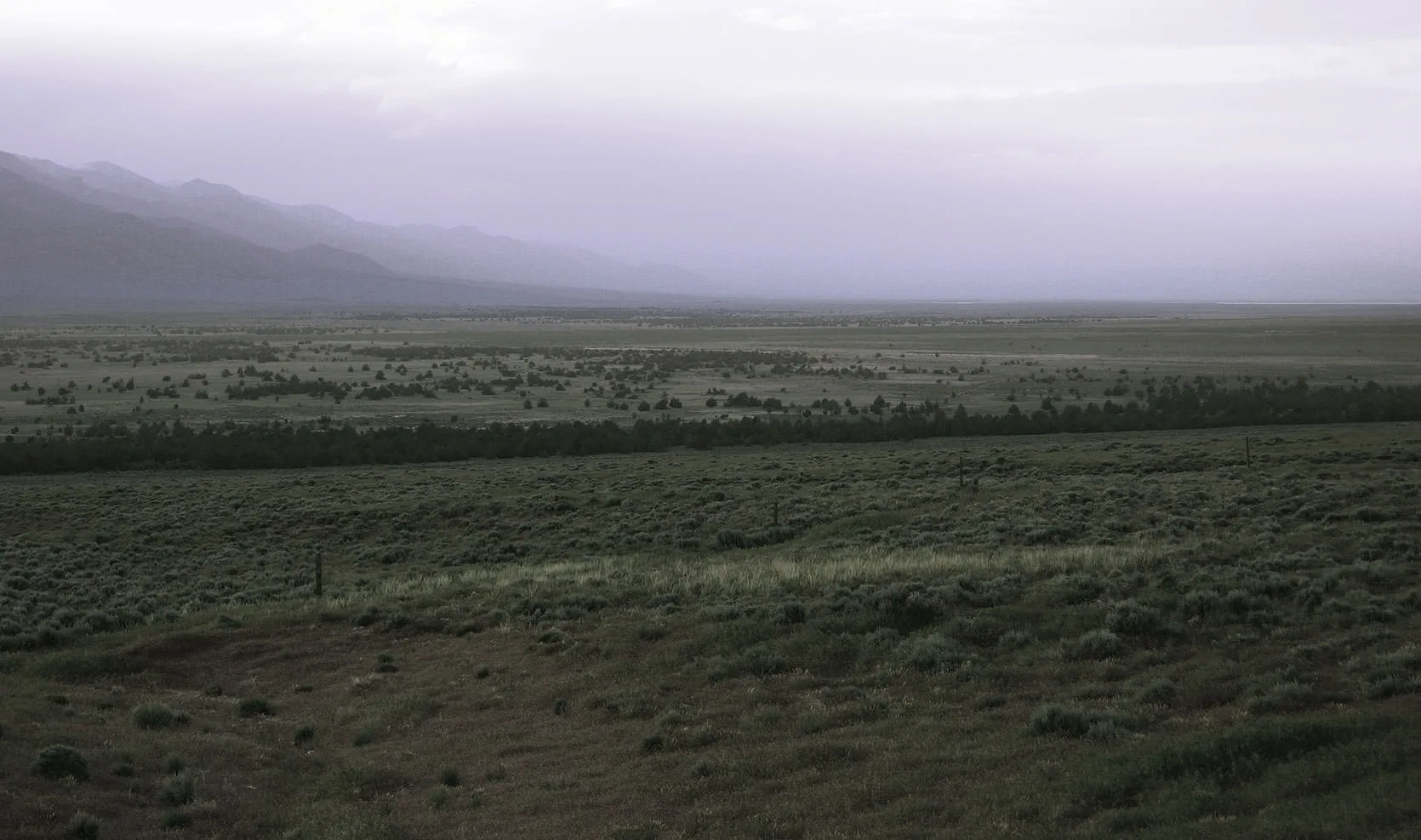 Dusk over a sagebrush and juniper basin in the Great Basin, distant ranges fading into hazy purple light