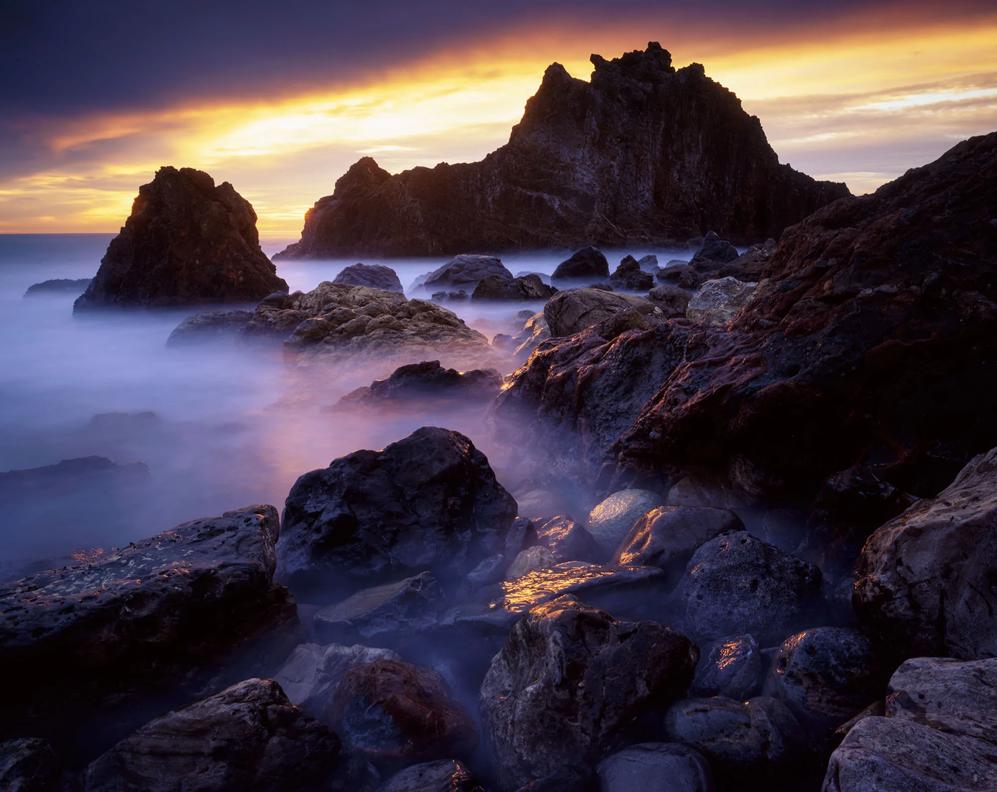 Jagged sea stacks above misty, long-exposure surf at sunset, the rocky Palos Verdes coast