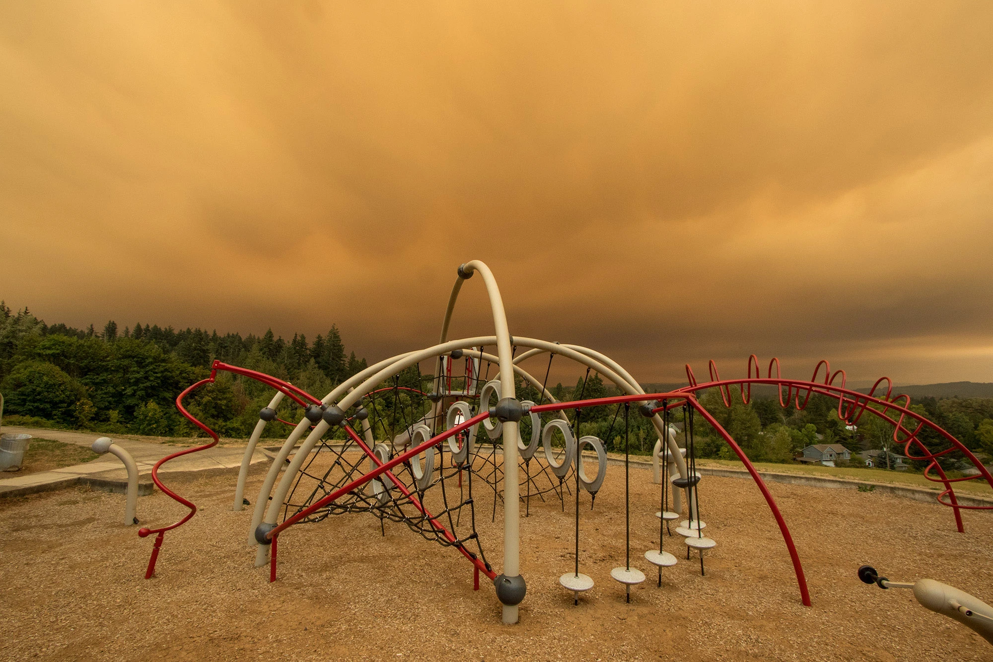 Playground in Portland, Oregon under dense orange wildfire smoke during the September 2020 wildfire convergence, when air quality reached hazardous levels and ranked among the worst in the world for days, illustrating how extreme heat, drought, and wind amplify wildfire impacts beyond ignition alone.
