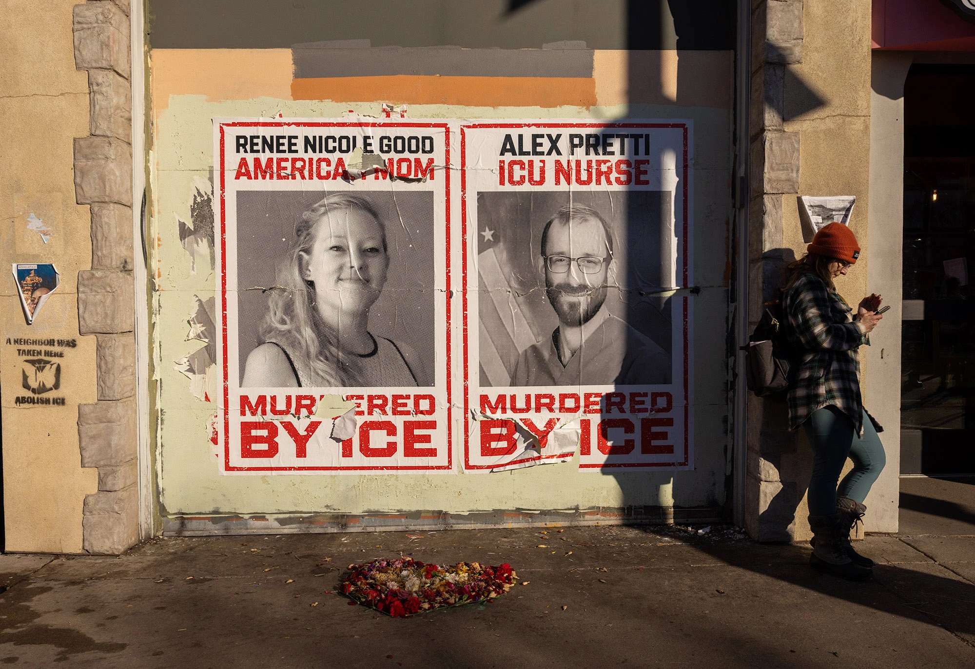 Posters pasted outside a Minneapolis coffee shop show portraits of Renee Good and Alex Pretti with bold text stating they were 'Murdered by ICE,' reflecting neighborhood outrage after their deaths during federal immigration enforcement operations.