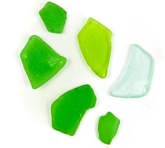Six pieces of frosted green and pale-blue sea glass arranged on white