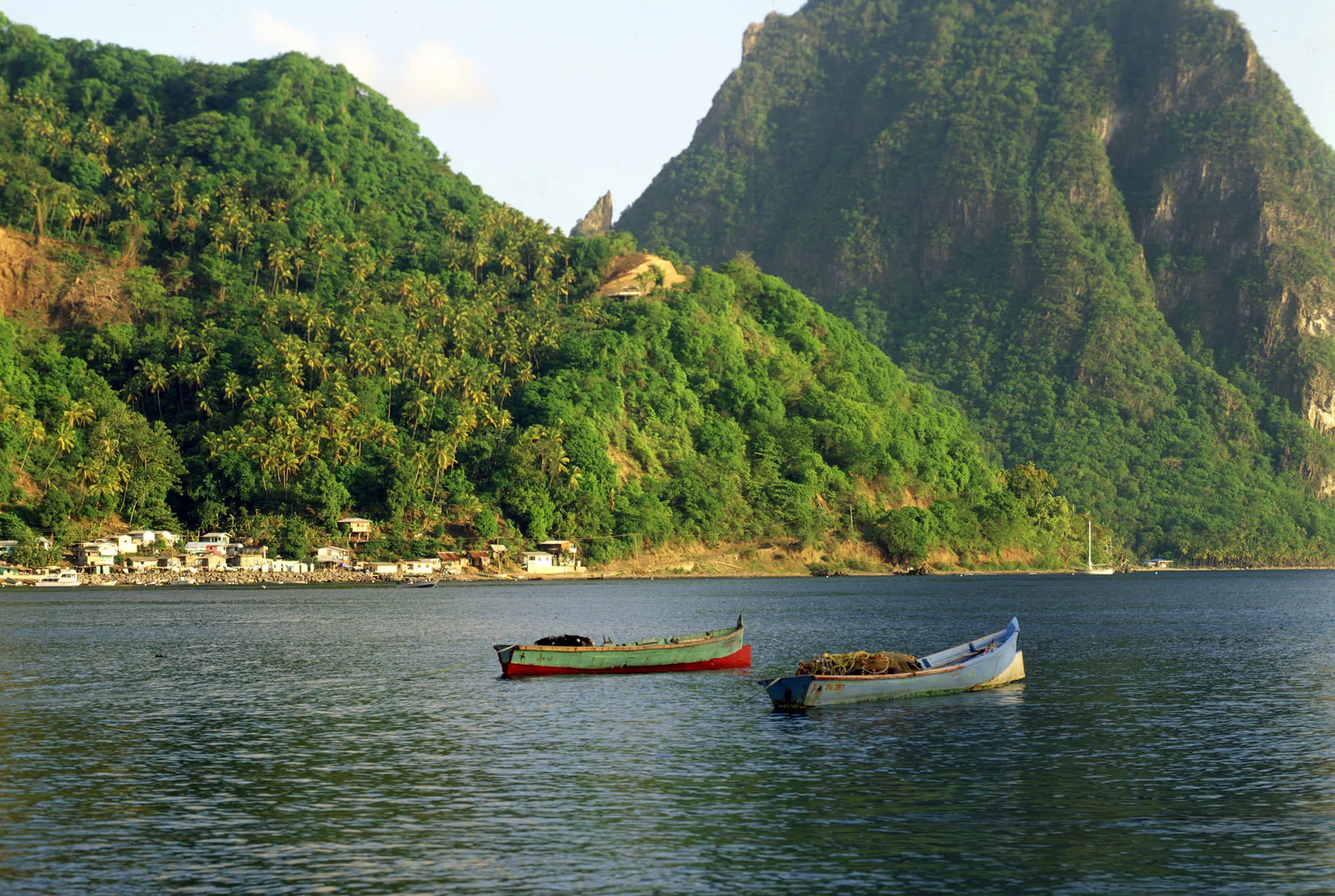 Two small fishing boats in the bay below green mountains at Soufrière, St. Lucia.