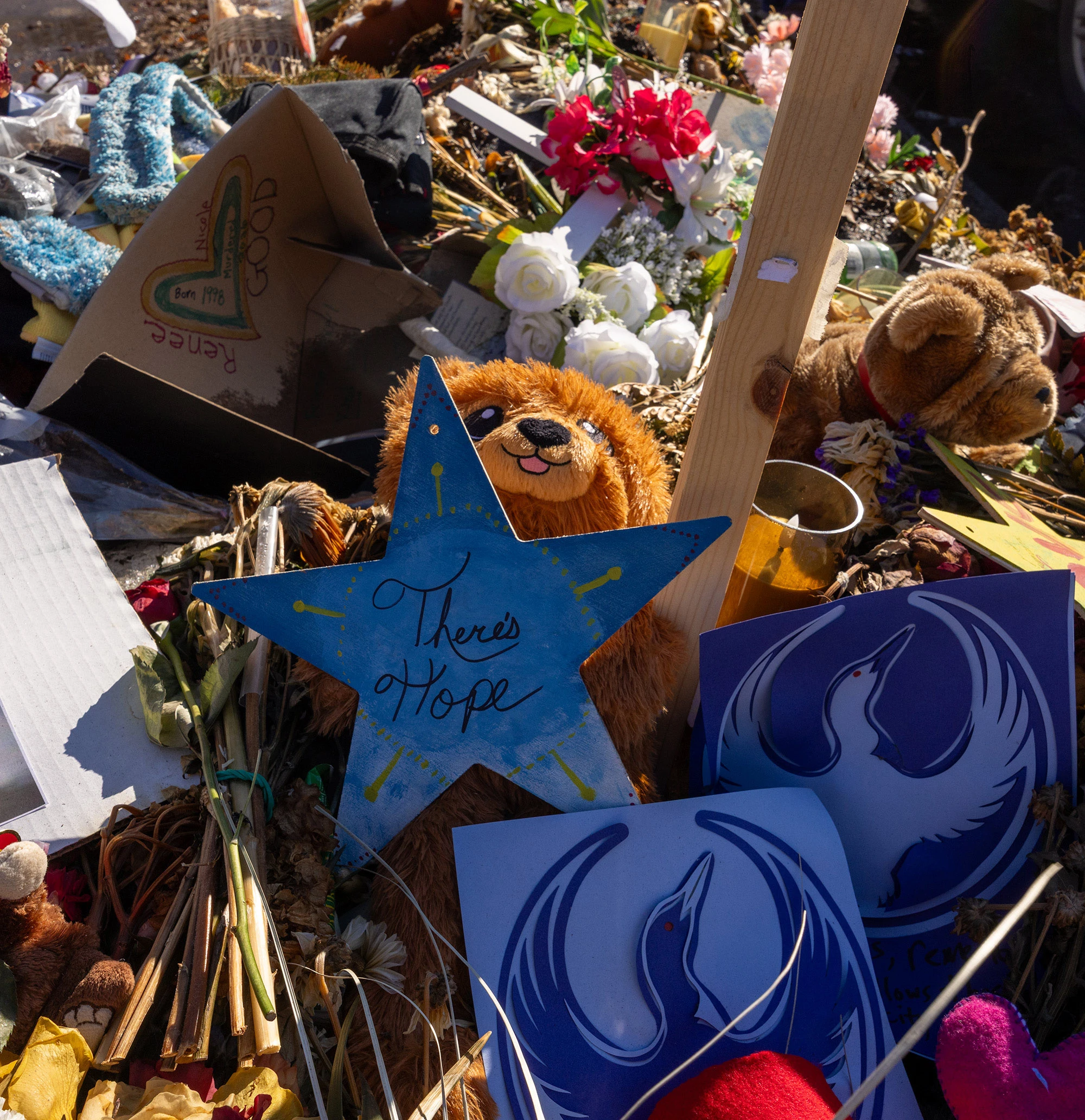 A star-shaped sign reading 'There's Hope' nestled among flowers, stuffed animals and handmade tributes at the memorial for Renée Good in Minneapolis.