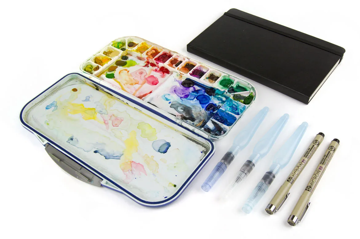 A waterproof watercolor palette case with mixed paints, water brushes, liner pens and a black sketchbook.